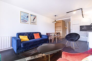 A living room with a blue couch and two posters one of which says combloux