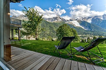 Two chairs on a deck with mountains in the background