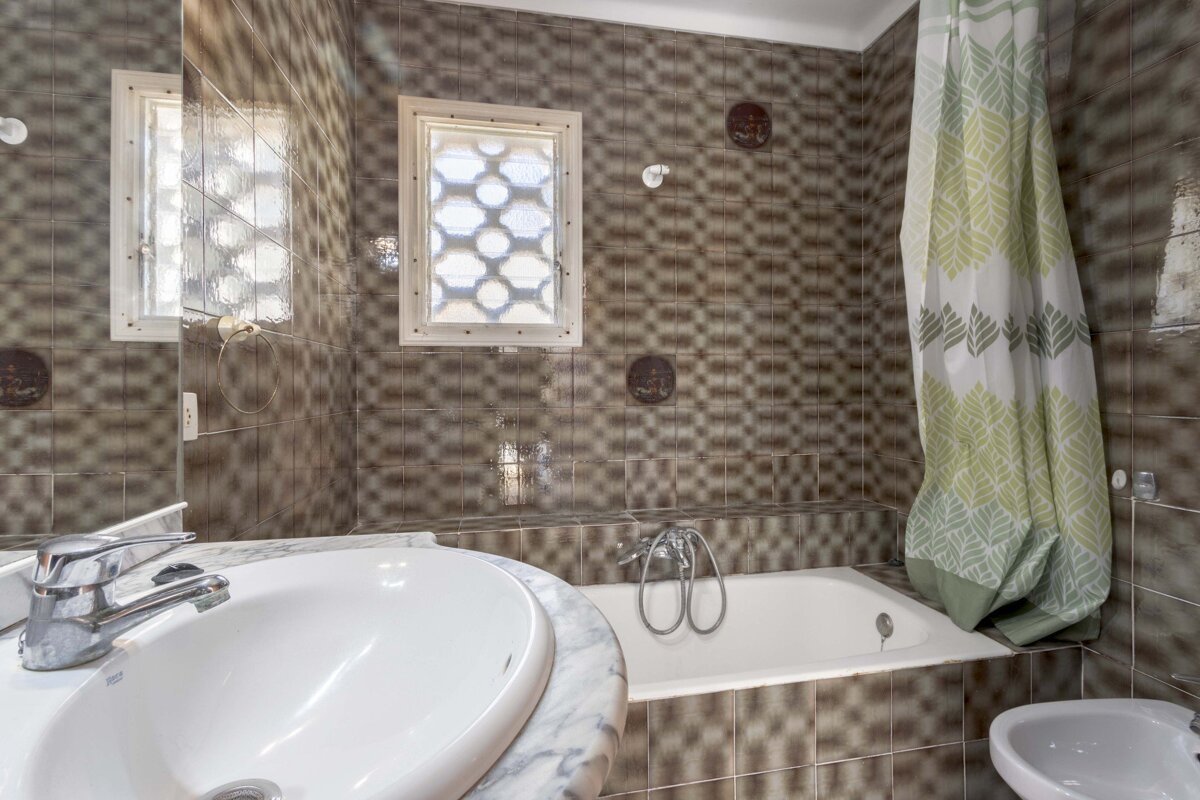 A bathroom with a sink and a bathtub with a green shower curtain