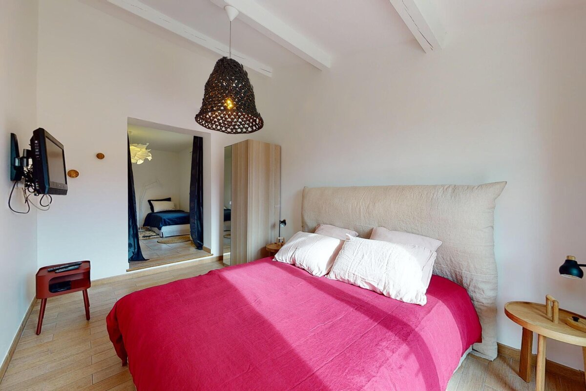 A bedroom with a red bed and a flat screen tv