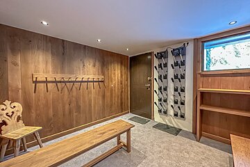 A wooden bench sits in a room next to a shoe rack