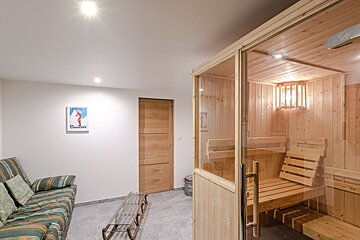 A room with a couch and a sauna with a picture of a woman on the wall