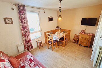 A living room with a table and chairs and a flat screen tv