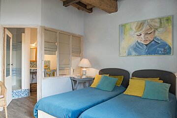 A bedroom with two beds and a painting on the wall