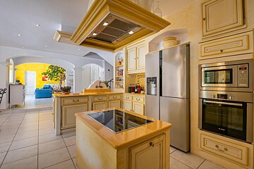 A kitchen with yellow cabinets and stainless steel appliances including a bosch oven