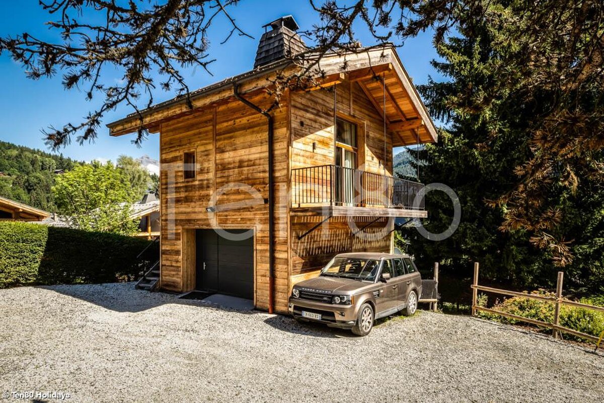 A range rover is parked in front of a wooden house