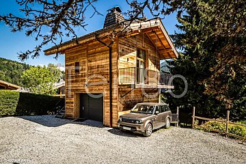 A range rover is parked in front of a wooden house