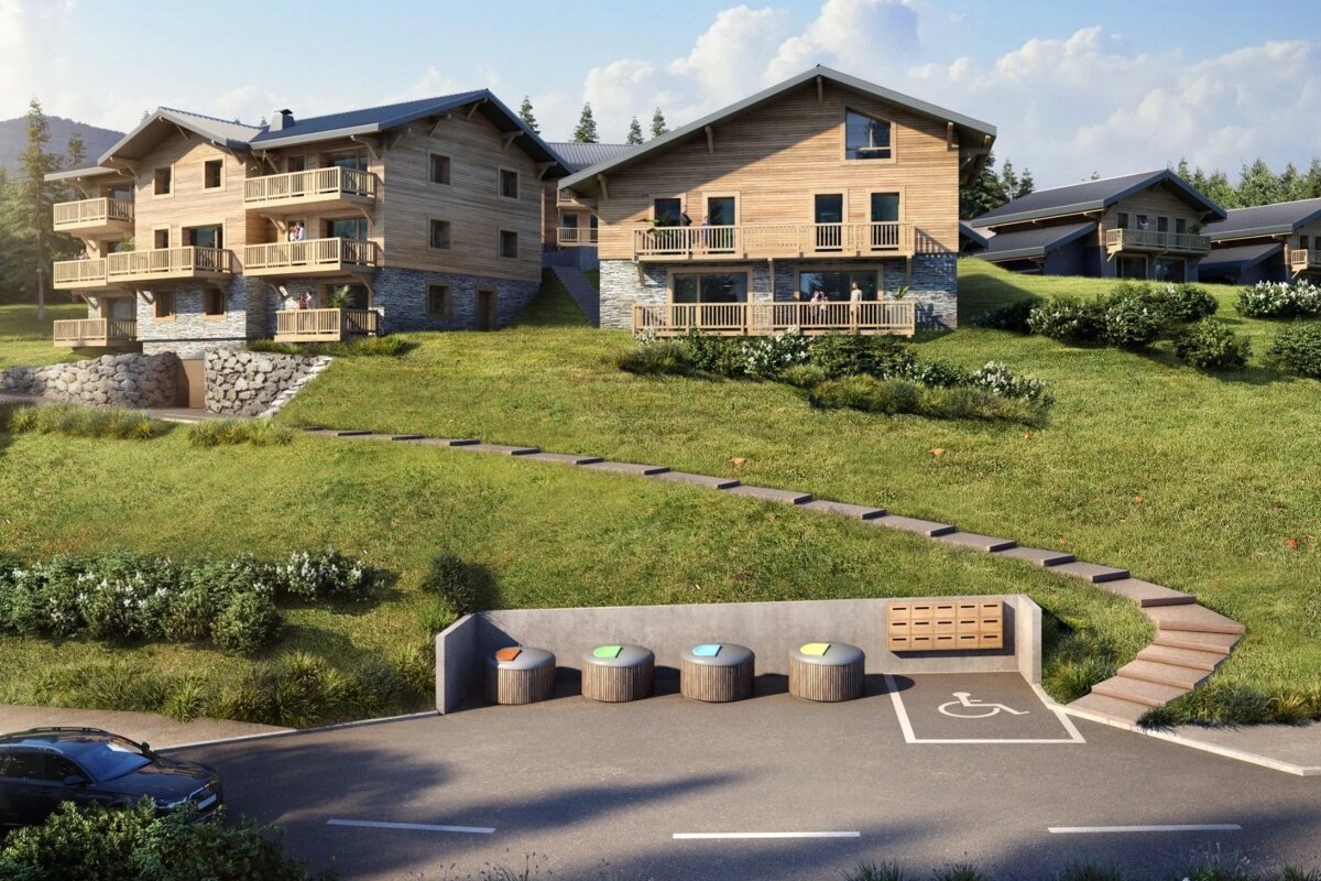 Wooden alpine chalets on a grassy hillside, with steps leading up from a parking lot below.