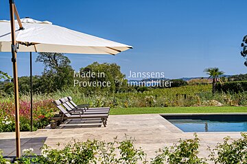 A white umbrella sits on a patio next to a swimming pool