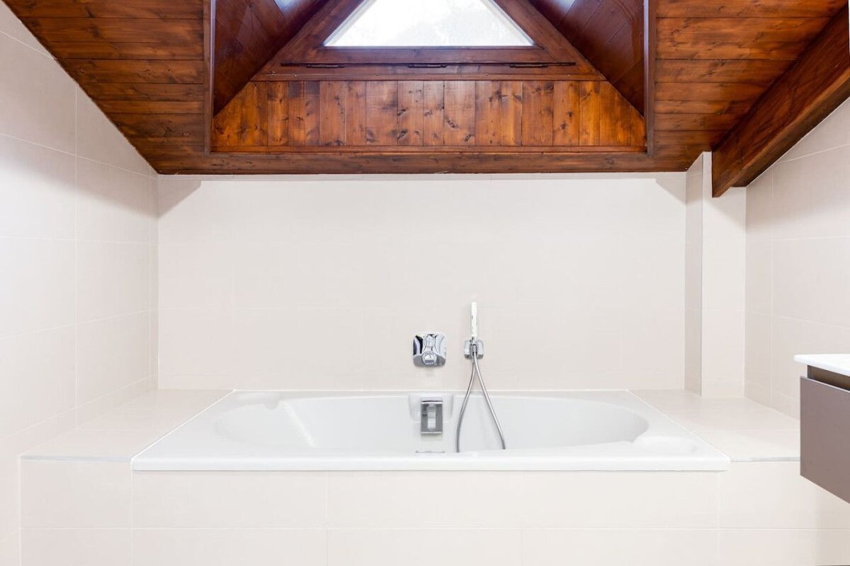 A bathtub in a bathroom with a wooden ceiling