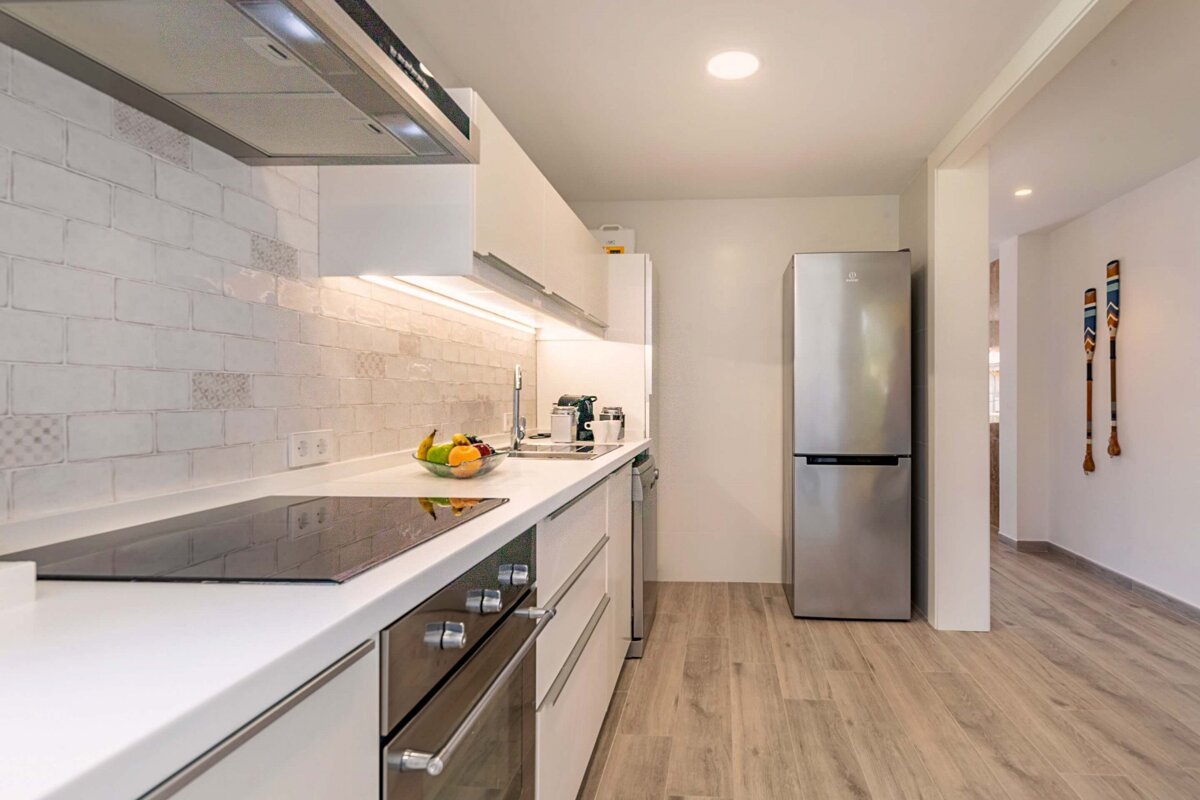 A kitchen with white cabinets and a stainless steel refrigerator