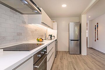 A kitchen with white cabinets and a stainless steel refrigerator