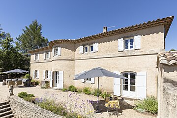 A large house with white shutters and an umbrella in front of it