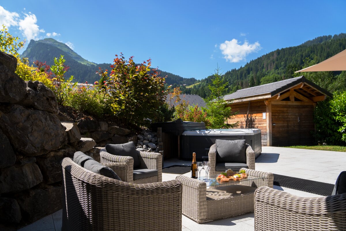 A patio with wicker furniture and a hot tub in the background