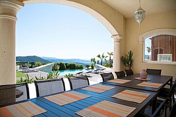 A patio with a table and chairs and a view of a pool