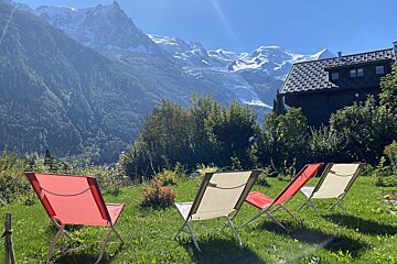 Red and white folding chairs in the grass with mountains in the background