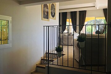 A staircase with a metal railing leading to a living room