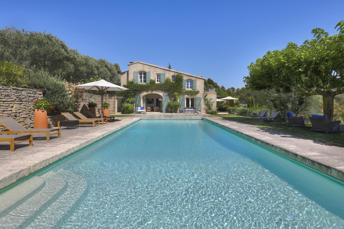 A large swimming pool in front of a stone house