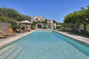 A large swimming pool in front of a stone house