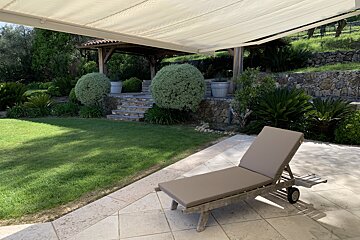 A lawn chair sits on a patio under an awning