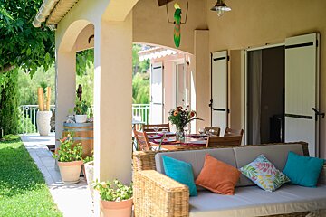 A patio with a couch and a surfboard hanging from the ceiling