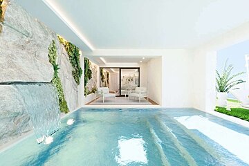 Serene indoor pool with a rock wall, waterfall, and lush vertical garden. Beyond, a chic seating area opens to a sunny outdoor view.