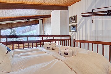 A bed with a view of a snowy mountain and a few towels that say alpine lodge