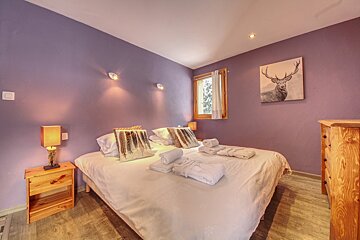 A bedroom with purple walls and a painting of a deer on the wall