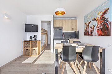 A kitchen with a table and chairs and a painting of cows on the wall