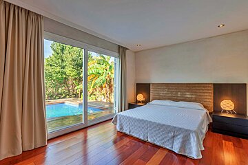 A bedroom with a sliding glass door leading to a pool