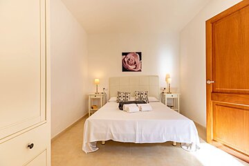 A bedroom with a bed and a picture of a rose on the wall