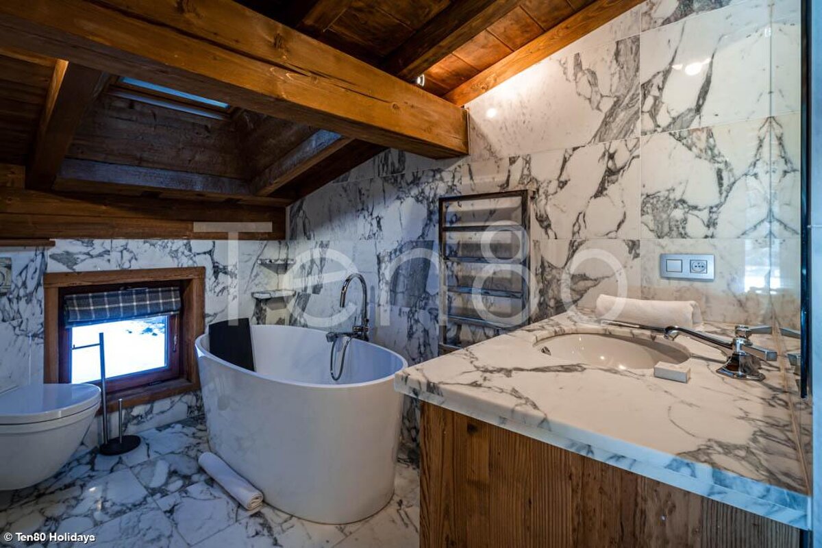 A bathroom with marble tiles and a bathtub and a sink