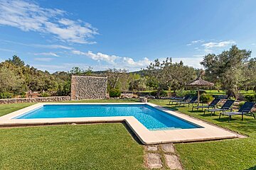 A large swimming pool surrounded by chairs and a stone wall
