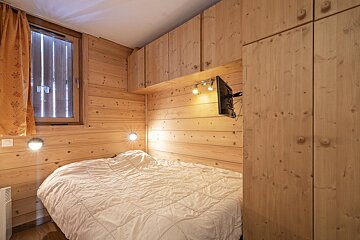 A bedroom with a bed and a television on the wall