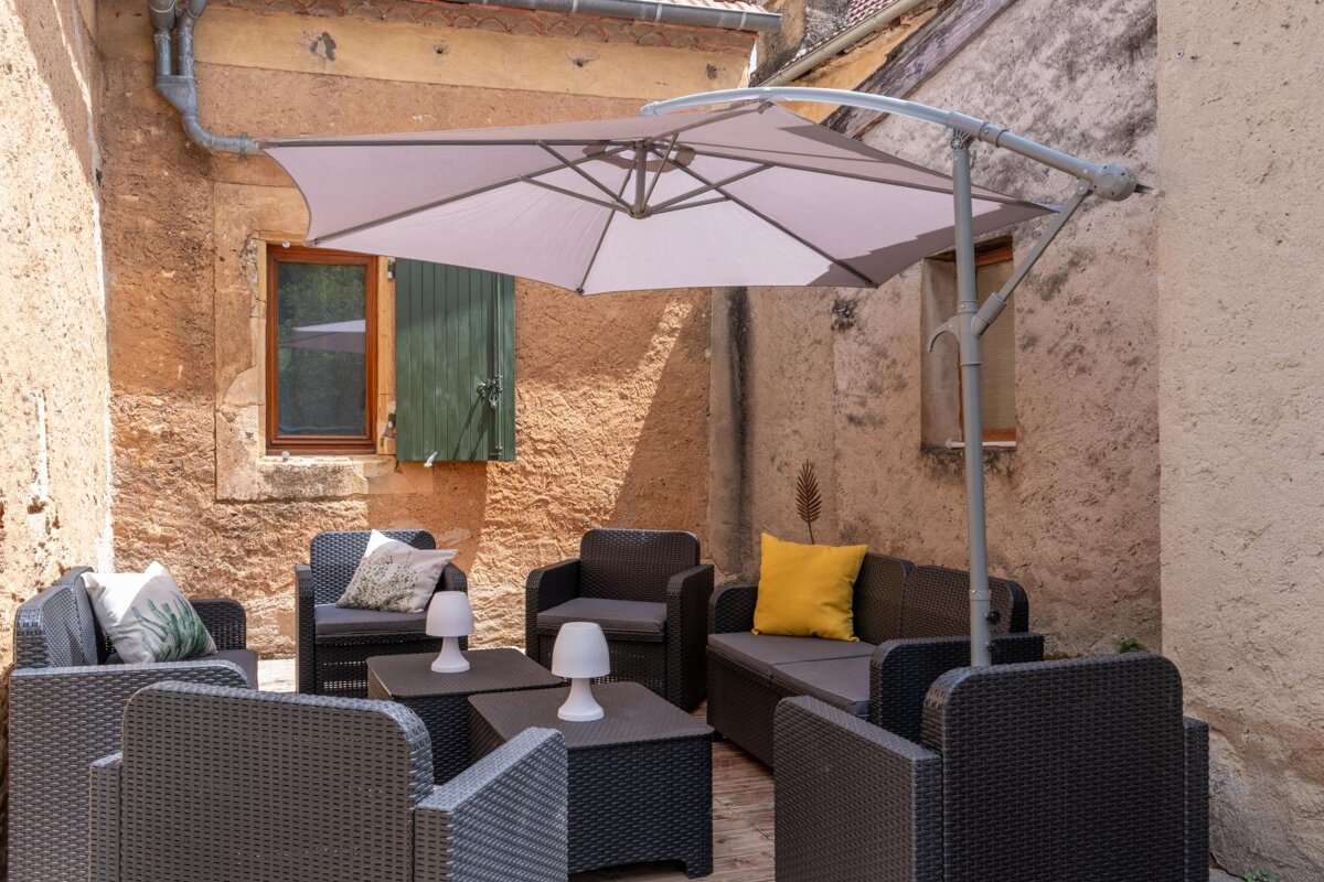 A patio area with chairs and tables under an umbrella