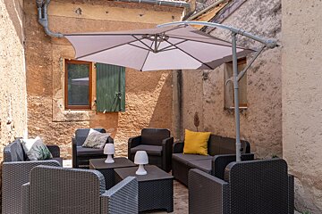 A patio area with chairs and tables under an umbrella