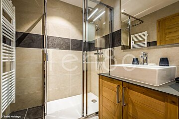 A bathroom with a sliding glass shower door and a sink