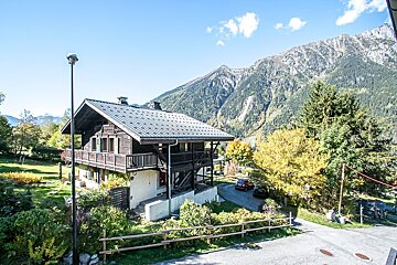A house in the mountains with a red car parked in front of it