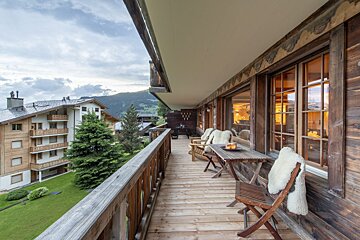 A wooden balcony with chairs and a table with candles on it