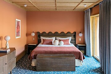 A bedroom with coral colored walls and a wooden headboard