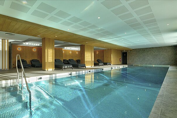 A large indoor swimming pool with chairs around it