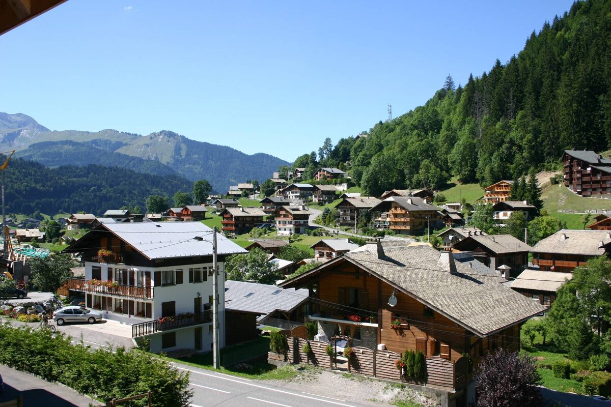 A row of houses on a hillside with mountains in the background