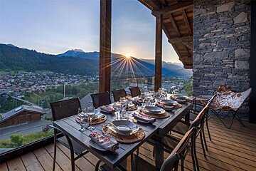 A dining table with a view of the mountains in the background