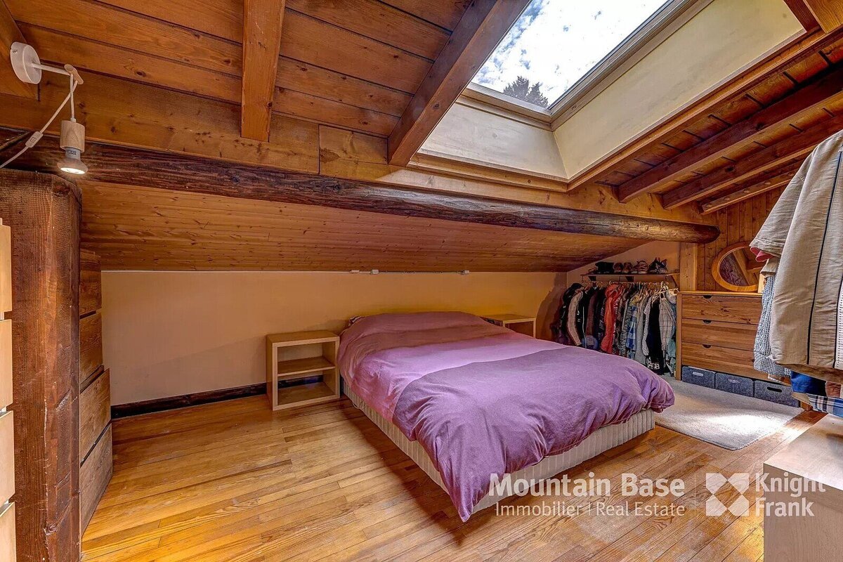 A bedroom with a bed and a skylight from mountain base