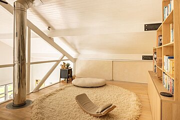 A chair sits on a rug in a room with bookshelves