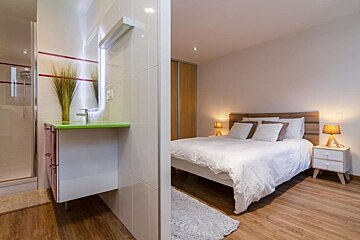 A bedroom with a bed and a bathroom behind it