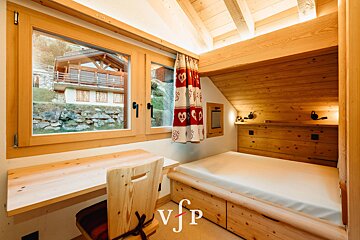 A bedroom with a bed and a desk with the letter v on it