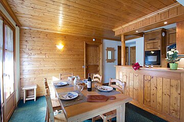 A dining room table with a bottle of wine on it