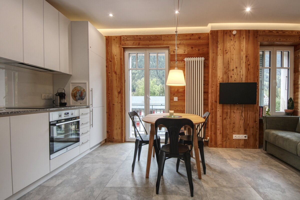A kitchen with a table and chairs and a flat screen tv