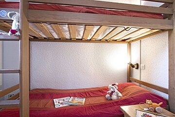 A bunk bed with a teddy bear and books on it